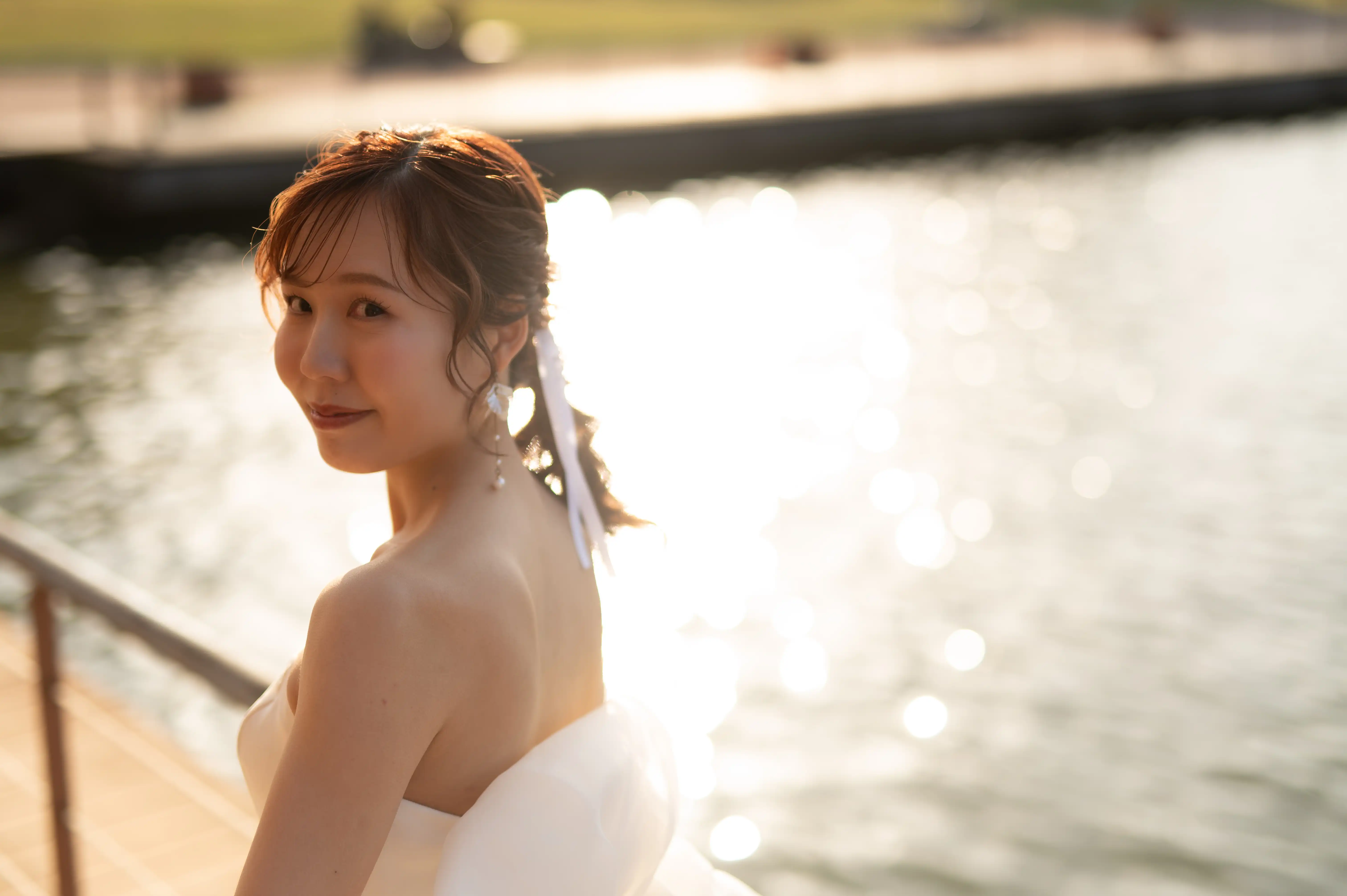 環水公園の水辺で逆光に包まれるウェディングドレス姿のブライド｜Oath & Ours 富山店